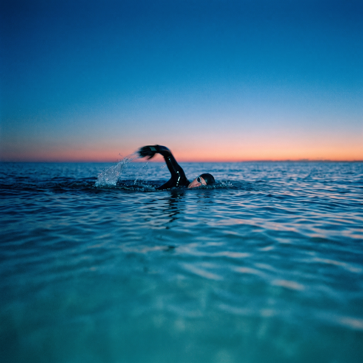 Open water swimmer mid stroke at dawn